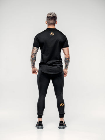 This is a rear view of Shane wearing the new standard long line t-shirt in black paired with the new standard joggers in black.  Showcasing the emblem in orange 