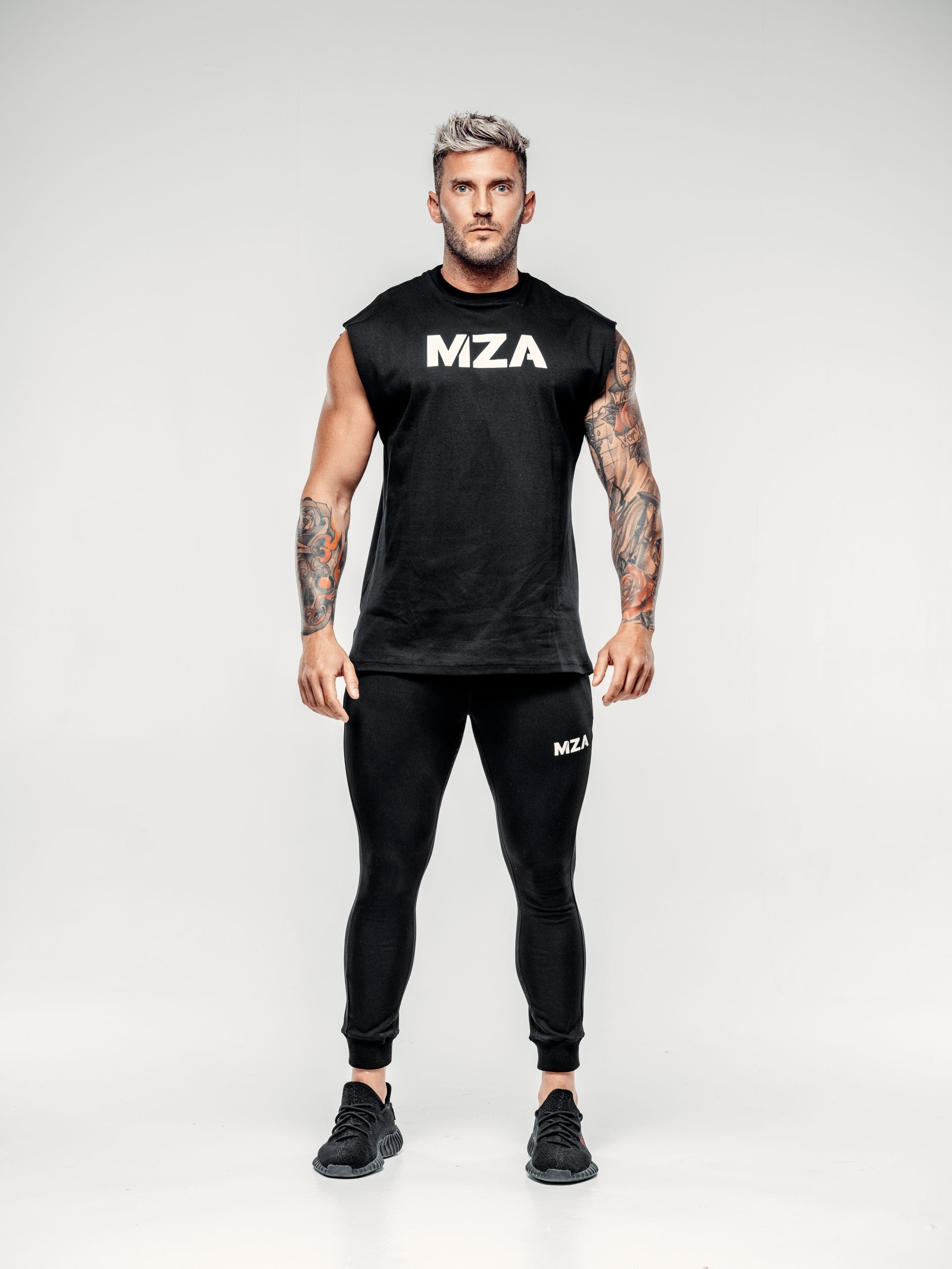 This is a full body shot of Shane wearing the new standard vest in black paired with the new standard joggers in black