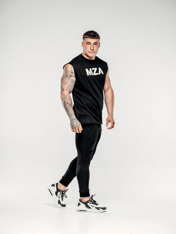 This is lewis mid step looking at the camera wearing the new standard vest in black paired with the new standard joggers in black