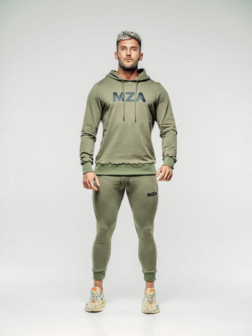 This is a full body shot of Shane straight on wearing the new standard hoodie in khaki. This features the MZA logo in white in the middle of his chest. Shane is also wearing the matching new standard joggers in khaki.