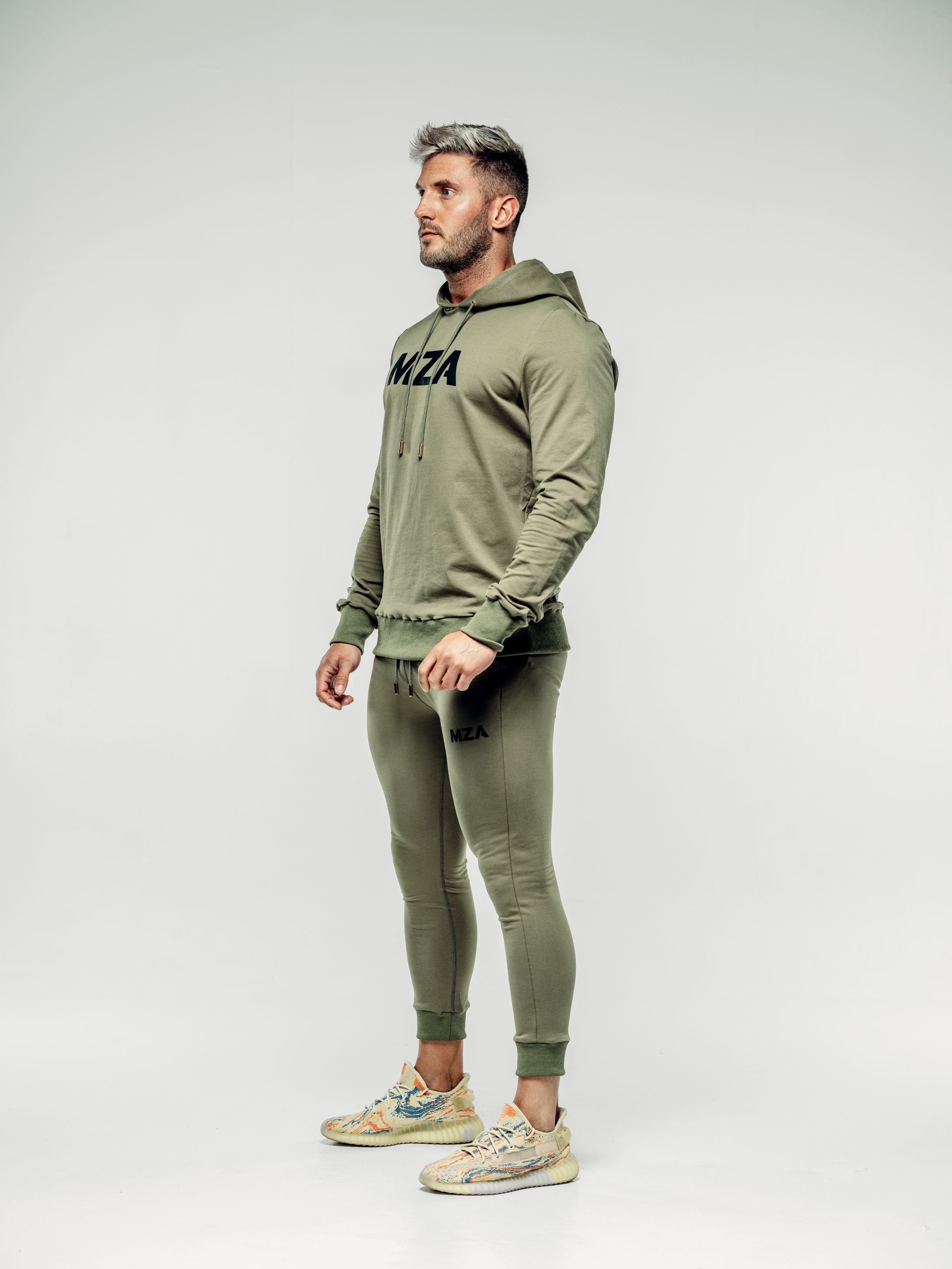 This is a 45 degree angle full body shot of Shane wearing the new standard hoodie in Khaki.  Shane is wearing the matching new standard joggers in khaki.