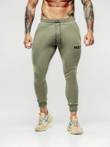 This is the bottom half of Shane showcasing the new standard joggers in khaki featuring the MZA logo in black on the left upper thigh