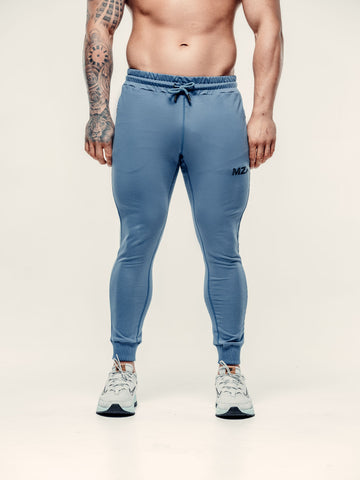 This is a front lower half image of Lewis wearing the new standard joggers in blue steel.  Featuring the MZA logo on the left thigh in black
