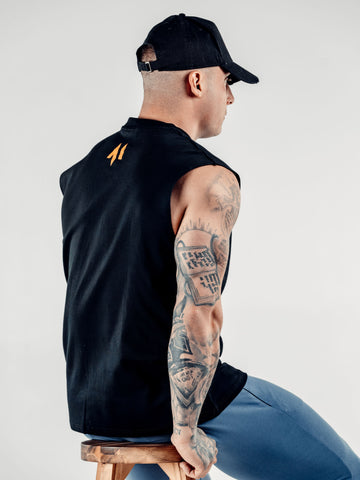 This is a rear sideview of Lewis wearing the new standard 3d distressed 5 panel in black.  It shows off the strap, buckle and how the peak fits from a side profile.  Lewis is also wearing the new standard vest in black featuring the M emblem at the top of his back.