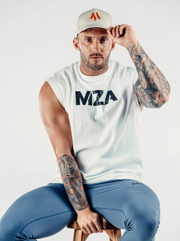 This is Shane sat straight on to the camera looking into the camera, holding the peak of the new standard 3d distressed 5 panel in stone.  Shane is holding on to the stool with his other hand.  Shane is also wearing the new standard vest in white with the new standard joggers in blue.